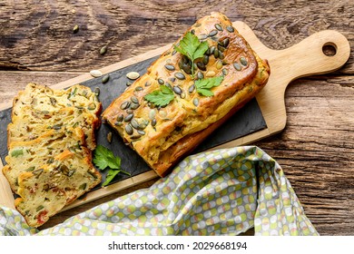 zucchini cake with dried tomatoes and pumpkin seed on a slate on wooden table 