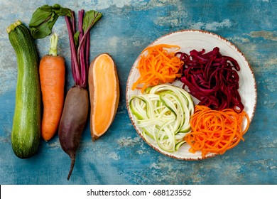 Zucchini, carrot, sweet potato and beetroot noodles on a plate. Top view, overhead. Blue rustic background - Powered by Shutterstock