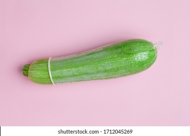 zucchini with condom on pastel pink color background. safe sex, sexy toy creative minimal concept, top view, flat lay