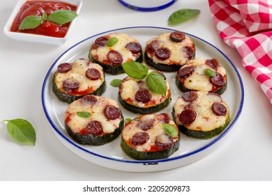 Zucchini Pizza Bites. Grilled Zucchini Slices With Tomato Sauce, Sausage, Basil And Melted Mozzarella Cheese Served On A White Plate.