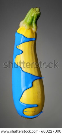 Zucchini with pouring blue paint on gray background. Fashion food concept.Creative.