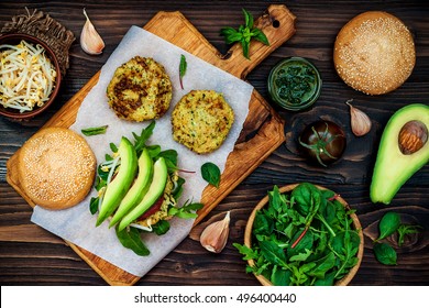 Zucchini Quinoa Veggie Burger With Pesto Sauce And Sprouts. Vegetarian Burger On A Cooking Sheet Ready To Prepare Hamburger. Top View, Overhead, Flat Lay