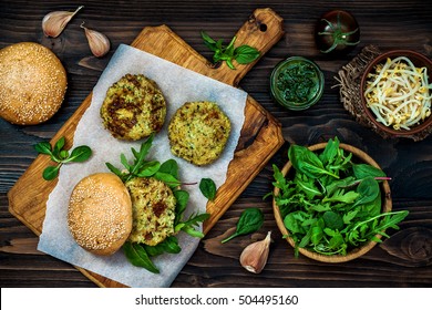 Zucchini Quinoa Veggie Burger With Pesto Sauce And Sprouts. Vegetarian Burger On A Cooking Sheet Ready To Prepare Hamburger. Top View, Overhead, Flat Lay