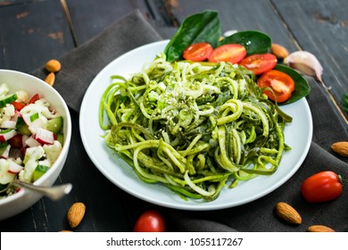 Zucchini Raw Vegan Pasta With Avocado Dip Sauce, Spinach Leaves And Cherry Tomatoes On Plate. On Dark Background. Vegetarian Healthy Food