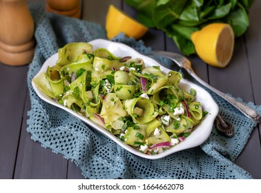 Zucchini Ribbon Salad with feta, red onion, and lemon dressing. Dark background, selective focus. - Powered by Shutterstock