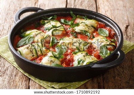 Zucchini rolls baked recipe with ricotta cheese and basil in tomato sauce in a pan on the table. horizontal
