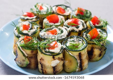 Zucchini rolls with cream cheese , tomatoes and dill . Healthy vegetarian food background