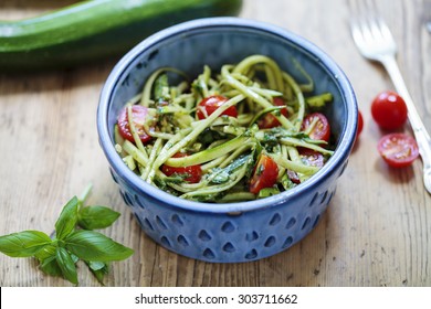 Zucchini spaghetti with rough basil and walnut pesto and cherry tomatoes - Powered by Shutterstock