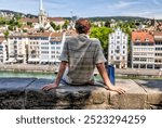 Zurich, Switzerland - July 26, 2024: A young man resting on a viewpoint wall in Zurich Switzerland
