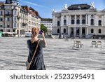 Zurich, Switzerland - July 26, 2024: A blonde woman taking photos of the Zurich Opera House
