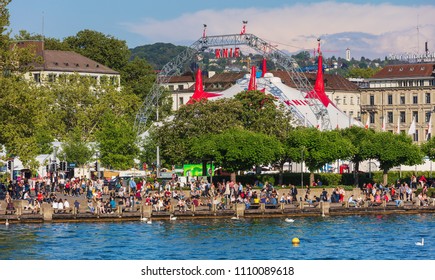 Zurich, Switzerland - May 11, 2018: people on the embankment of Lake Zurich in the city of Zurich, venue of the Circus Knie in the background. Zurich is the largest city in Switzerland.