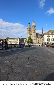 ZURICH, SWITZERLAND - MAY 30, 2019: Grossmünster From Münsterbrücke Bridge With Lots Of Tourists In The View. 