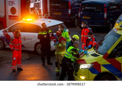 Zutphen, The Netherlands - December 8, 2020: Task force of ambulance personnel, police and fire fighters in face masks deliberating and organizing at an accident scene