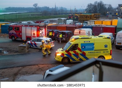 Zutphen, The Netherlands - December 8, 2020: Ambulance arriving and fire fighters rushing towards scene of an accident at a construction site with the river IJssel in the background at sunrise