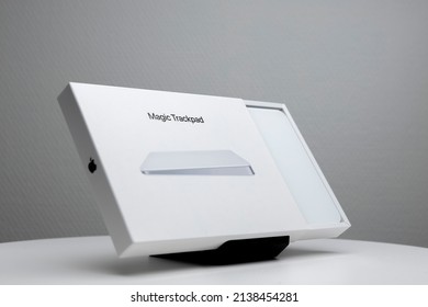 Zutphen, The Netherlands - March 2022: Gray Backdrop With White Half Opened Package Box Of Mac Apple Magic Trackpad On Display Stand. Studio Technology Design Product Still Life.