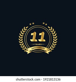 11th golden anniversary logo, with shiny ring and golden ribbon, laurel wreath isolated on navy blue background