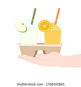 The 2 glasses of juice smooties (apple, orange). They are in the cup carier that hold in hand. take a way beverages. home delivery concept. organic and healthy soft drink for summer.