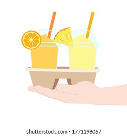 The 2 glasses of juice smooties (orange, pineapple). They are in the cup carier that hold in hand. take a way beverages. home delivery concept. organic and healthy soft drink for summer.