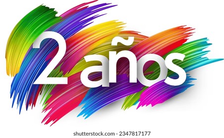 2 years at spanish paper word sign with colorful spectrum paint brush strokes over white. Vector illustration.