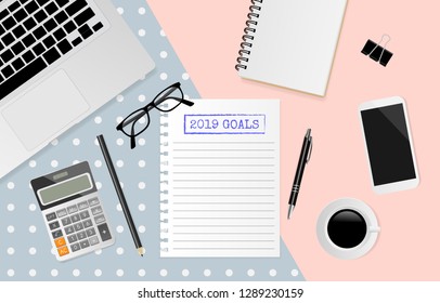 2019 goals text on white note paper with office supplies on pastel background