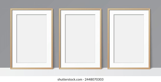 3 Blanck poster wooden frames leaning against a grey wall background. Poster gallery vector mockup for art, image, or text placement.