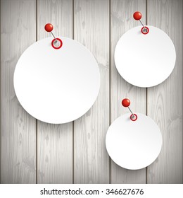 3 white paper circle stickers with red pins on the wooden background. Eps 10 vector file.