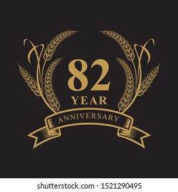 82 golden anniversary logo with ring and ribbon, laurel wreath vector design isolated on black background