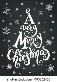 'A very merry Christmas' handwritten quote in a xmas tree on chalkboard background.. Unique hand lettering. Great design element for greeting cards, banners and holidays flyers.