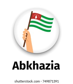 Abkhazia flag in hand, round icon with shadow isolated on white. Human hand holding flag, vector illustration