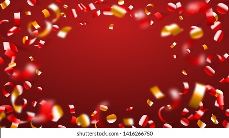 Abstract background of flying shiny confetti and pieces of serpentine, golden and yellow on red