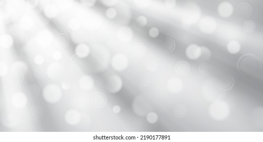 Abstract background in white and gray colors with diverging rays of light and small translucent circles with bokeh effect