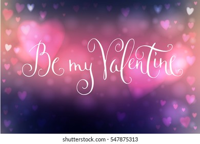 Abstract blue and pink blur background with heart-shaped lights over it and hand written Valentine's day greetings.