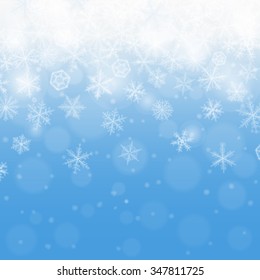 Abstract blue winter background with blurred various snowflakes.