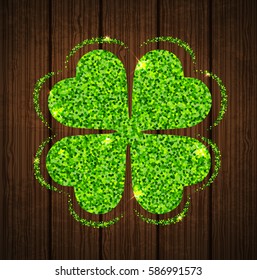 Abstract green glitter clover leaf on a wooden background