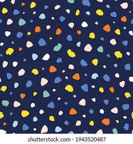 Abstract hand drawn dots and irregular shapes randomly placed seamless repeat pattern. Multicolor confetti like all over print with dark blue background.