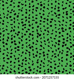 Abstract seamless pattern from small shapes. Simple background of irregular spots. Abstract wild animal skin print. Random spaced black spots. Vector illustration on green background