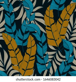 Resumen de un patrón tropical sin fisuras con plantas azules y beige brillantes y hojas sobre un fondo negro. 
 Papel tapiz de la selva exótica. 
 Impresión Hawaii de verano de moda. 
Impresión y textiles. 