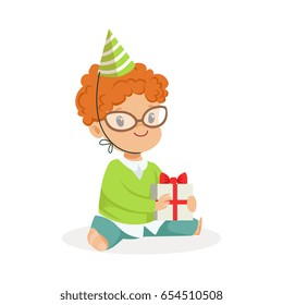 Adorable baby boy wearing a green party hat sitting with gift box. Childrens birthday party colorful cartoon character vector Illustration