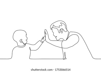 adult and child give each other five. Father (man) with a boy (son) beat each other in the palm of their hand, they both smile at each other.