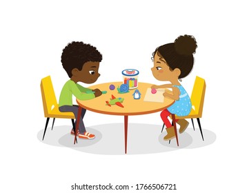 African American Boy and Girl sit at the round table and sculpt clay figures. Fine motor skills development. Sculpting activity in the art class. Boy and Girl Draw Pictures with paints and pencils. Po