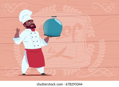 African American Chef Cook Holding Tray With Dish Smiling Cartoon In White Restaurant Uniform Over Wooden Textured Background Flat Vector Illustration