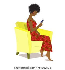 African American  girl sitting in a yellow armchair and using a mobile phone