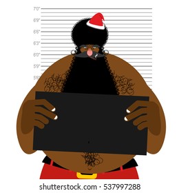 African American Santa at police station. Mugshot Black Santa gangster. Afro hairstyle and red Christmas hat.