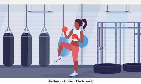 african american woman boxer doing exercises hitting punching bag girl fighter training workout fight club interior healthy lifestyle concept flat horizontal