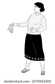 African American woman stands and holds a knitted mitten and a ball of thread in her hands