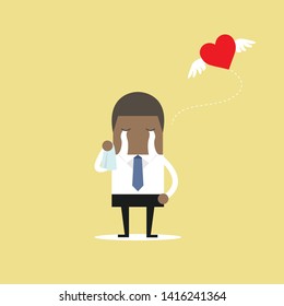 African businessman crying broken heart with heart flying away.