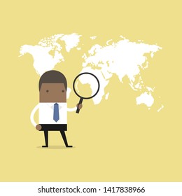 African businessman holding magnifying glass finding over world map.