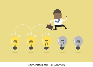 African businessman jump on light bulbs.