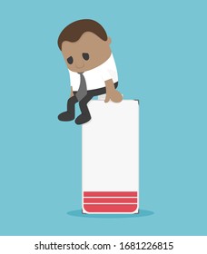 African businessman sitting on the battery is about to run out, showing that he is discouraged