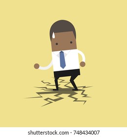 African businessman standing on cracking floor.